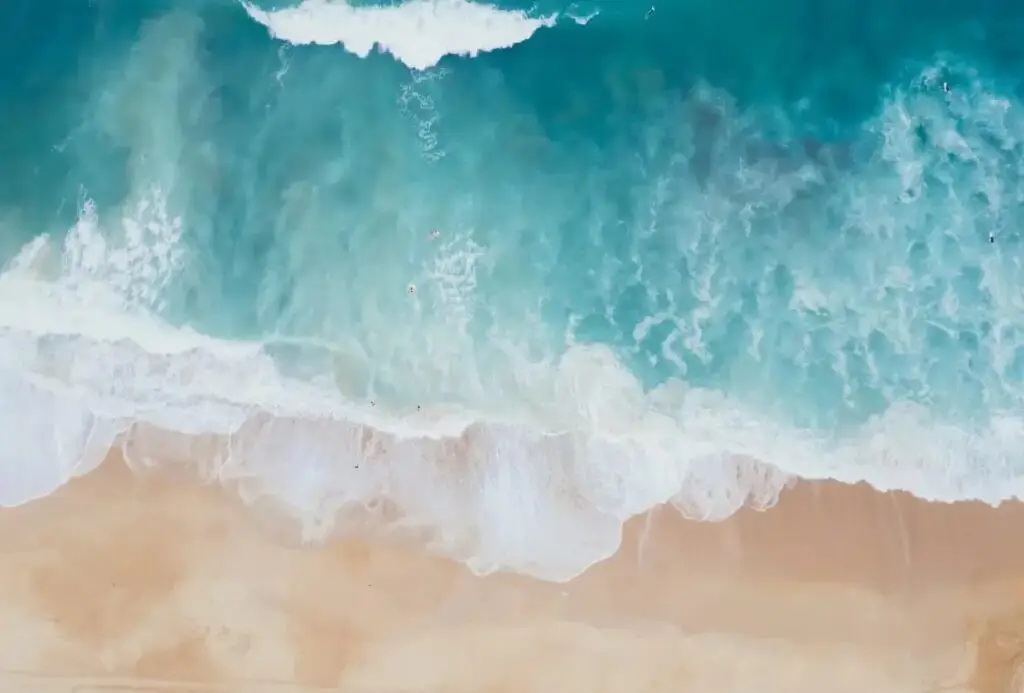 Vertical aerial view taken by a drone of waves on a beach with turquoise water